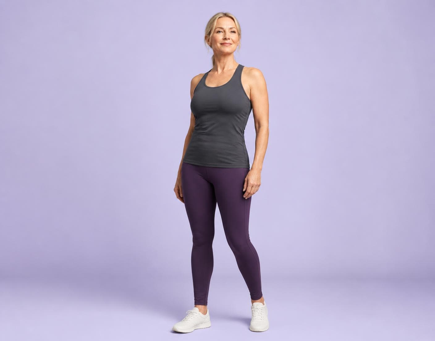 Woman in activewear standing against a soft lilac studio background
